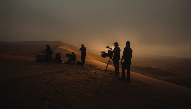 Film crew silhouetted on a desert dune at golden hour — production services, Abu Dhabi.