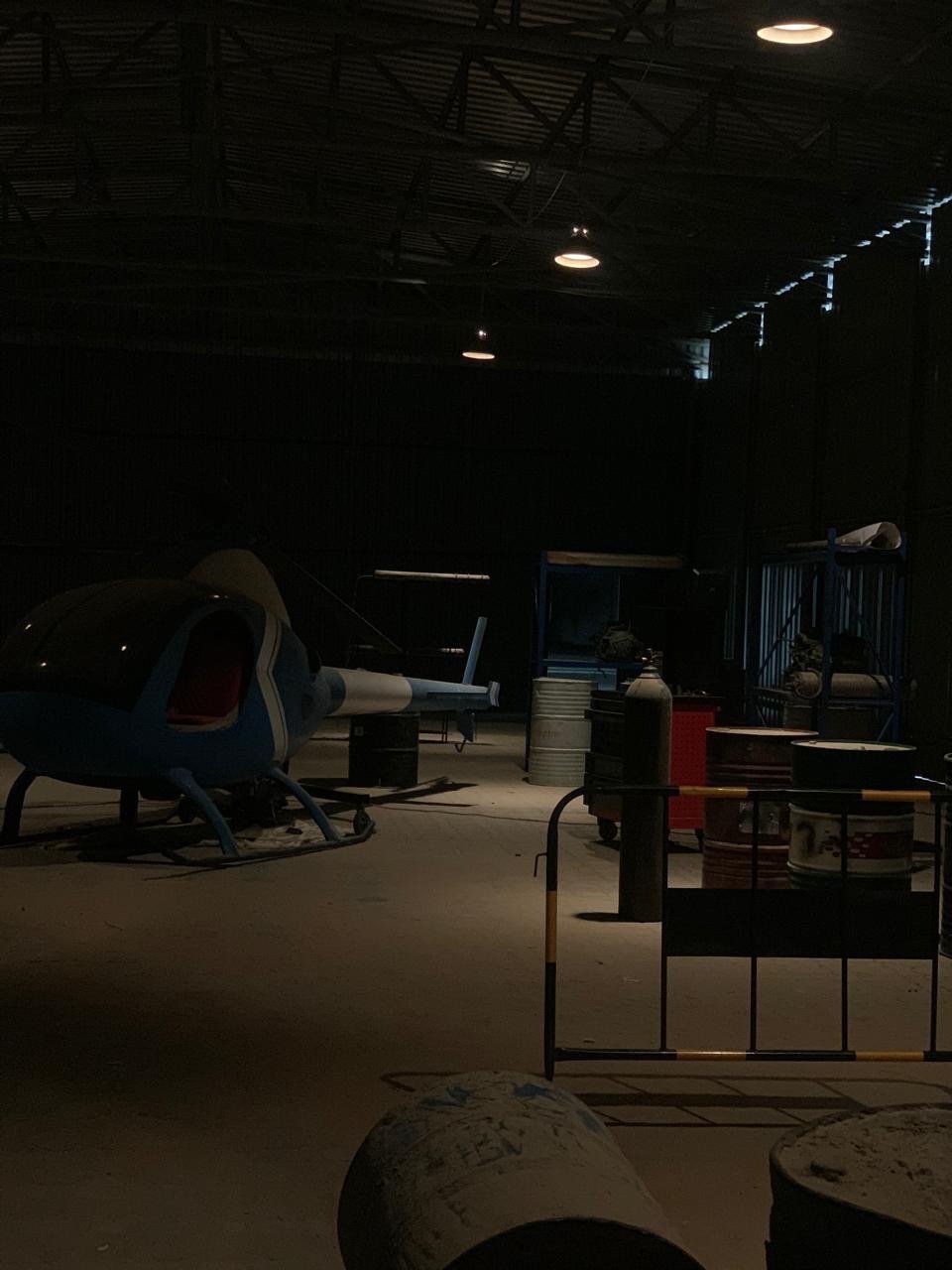 On-location film production set inside a dimly lit hangar with a helicopter — Over Exposure Productions, Abu Dhabi.