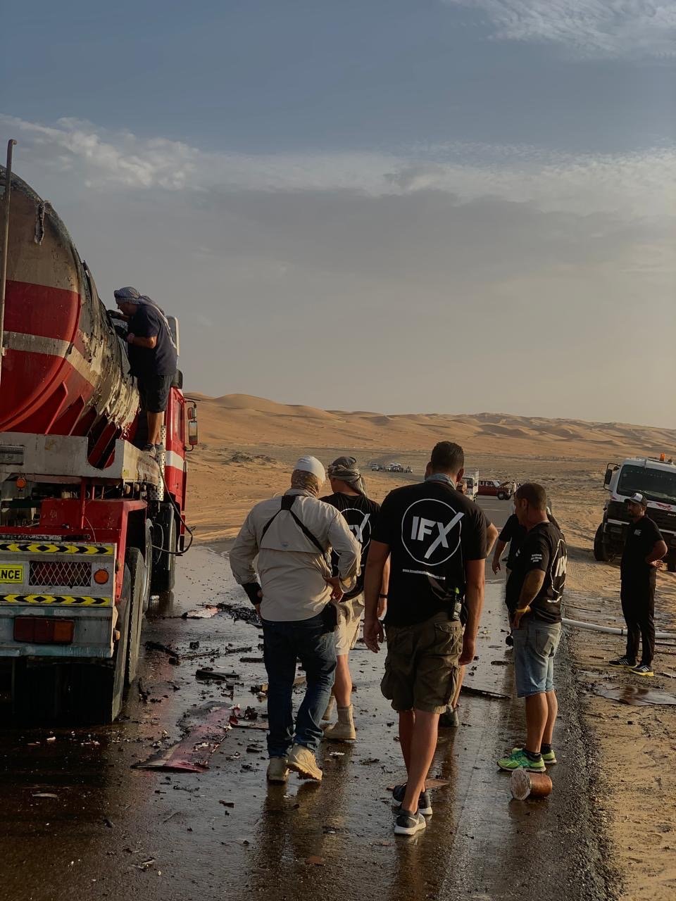 Production crew on a desert location shoot at golden hour beside a tanker truck — corporate video production, UAE.